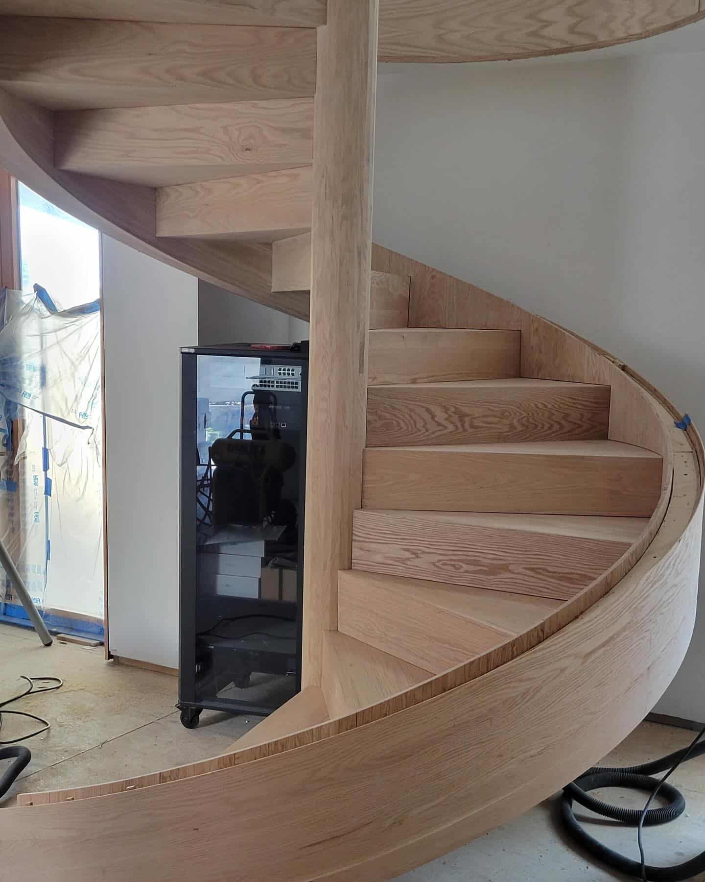 Completed spiral stair wrapped in white oak with inset groove for glass guardrail.